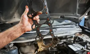 Uszczelka pod głowicą kosztuje sporo, a ta wygląda na zużytą. Mechanik pokazuje ją po demontażu silnika.