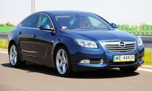 Niebieski Opel Insignia 2.0 CDTI pędzi po drodze. Kierowca skupiony na trasie.