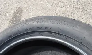 Opona samochodowa z napisem "ULTRA HIGH PERFORMANCE", rozmiar 225/50 R17 98V. Wygląda jak kormoran nurkujący w wodę.