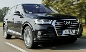 Czarny Audi Q7 2025 pędzi po drodze, otoczony zielenią drzew.