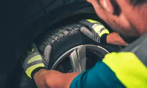 Mechanik w rękawicach z odblaskami sprawdza stan opony. Fwd.