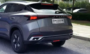 Szary OMODA 5 Hybrid z tyłu, z widocznym napisem "OMODA Hybrid" na klapie bagażnika. Nowoczesne światła LED i sportowy dyfuzor.