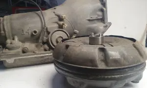 Zużyty sprzęgło hydrokinetyczne i skrzynia biegów leżą na stole.