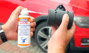 Czyszczenie przepływomierza preparatem Liqui Moly. Ręka trzyma puszkę z preparatem i aplikuje go na element.