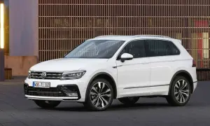 Biały Volkswagen Tiguan 2019 z eleganckimi felgami stoi przed nowoczesnym budynkiem z drewnianą fasadą.