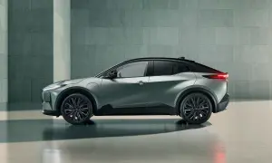 Nowoczesna, srebrna Toyota Hybrid w profilu, z czarnym dachem i przyciemnianymi szybami, stoi na tle betonowej ściany.