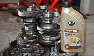 Zbliżenie na mechanizm skrzyni biegów i butelkę oleju przekładniowego 75W-90.