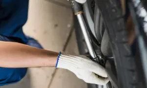 Mechanik w białej rękawicy dokręca śruby koła kluczem dynamometrycznym, dbając o to, z jaką siłą dokręcać koła.