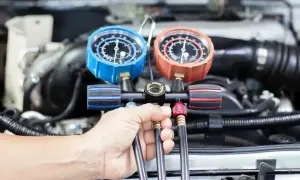 Mechanik sprawdza ciśnienie w układzie klimatyzacji. Dowiedz się, ile kosztuje nabicie klimatyzacji w Twoim samochodzie.