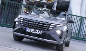 Nowoczesny Hyundai hybryda z charakterystycznym grillem i światłami LED, zaparkowany przy przemysłowym ogrodzeniu.
