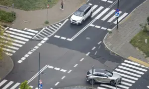Skrzyżowanie z pasami i znakami drogowymi. Samochody zbliżają się do przejść, stosując zasadę prawej ręki.