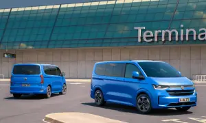 Dwa niebieskie Volkswageny Caravelle stoją przed budynkiem terminala lotniska.