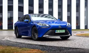 Niebieska Toyota Mirai, samochód przyszłości, zaparkowana przed nowoczesnym budynkiem.