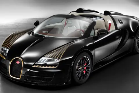 Czarny Bugatti Veyron z złotymi pasami na masce i złotą obwódką grilla. Kabriolet z jasnym wnętrzem.