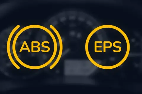 Dwa żółte okręgi z napisami ABS i EPS na tle deski rozdzielczej. ABS to system zapobiegający blokowaniu kół podczas hamowania.