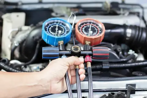 Mechanik sprawdza ciśnienie w układzie klimatyzacji. Dowiedz się, ile kosztuje nabicie klimatyzacji w Twoim samochodzie.
