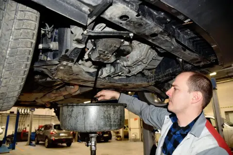 Mechanik spuszcza stary olej z silnika. Zastanawiasz się, ile trwa wymiana oleju? Zwykle to około 30-60 minut.
