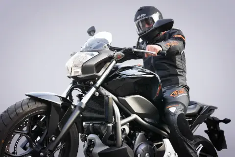 Motocyklista w kasku i kombinezonie siedzi na czarnym motocyklu. Zastanawiasz się, prawo jazdy a1 od ilu lat?