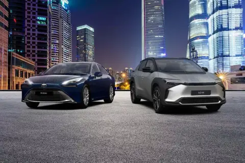 Dwa samochody, Toyota Mirai i bZ4X, na tle nocnego miasta. Zastanawiasz się, ile kosztuje samochód elektryczny?