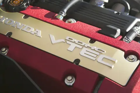 Złota pokrywa silnika Honda z napisem VTEC. Czerwone, teksturowane wykończenie dodaje sportowego charakteru.