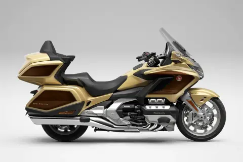 Złoty Honda Goldwing, luksusowy motocykl turystyczny z brązowymi akcentami, gotowy na dalekie podróże.