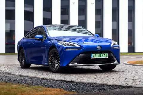 Niebieska Toyota Mirai, samochód przyszłości, zaparkowana przed nowoczesnym budynkiem.