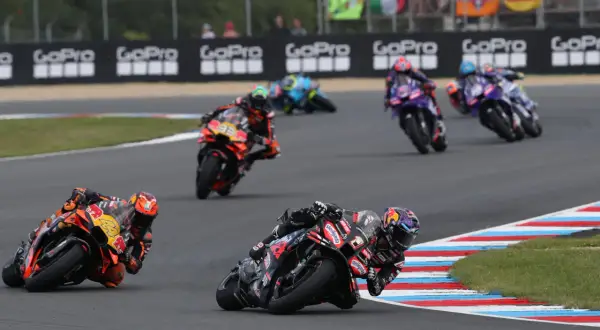 Motocykliści ścigają się na torze, tworząc dynamiczny obraz, który mógłby znaleźć się w każdym motogp kalendarz.