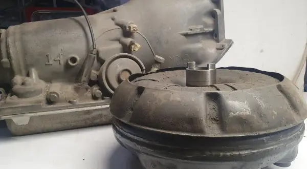 Zużyty sprzęgło hydrokinetyczne i skrzynia biegów leżą na stole.