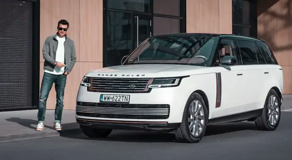 Elegancki mężczyzna obok białego Range Rovera. Sprawdź aktualną range rover cena i dowiedz się więcej o tym luksusowym SUV-ie.