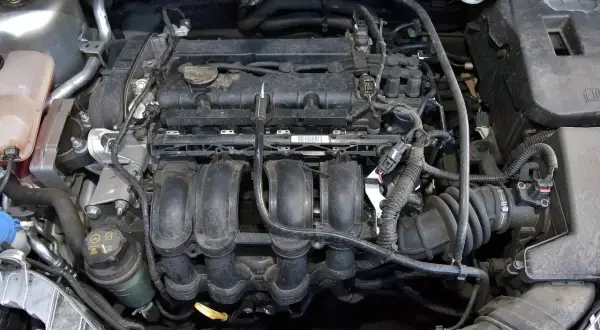 Silnik Ford Focus MK3 1.6 benzyna, widok z góry. Widać kolektor dolotowy, cewki zapłonowe i inne elementy.