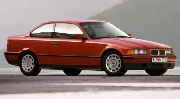 Czerwone BMW E36 coupe z lat 90. na tle szarego nieba. Klasyka motoryzacji.
