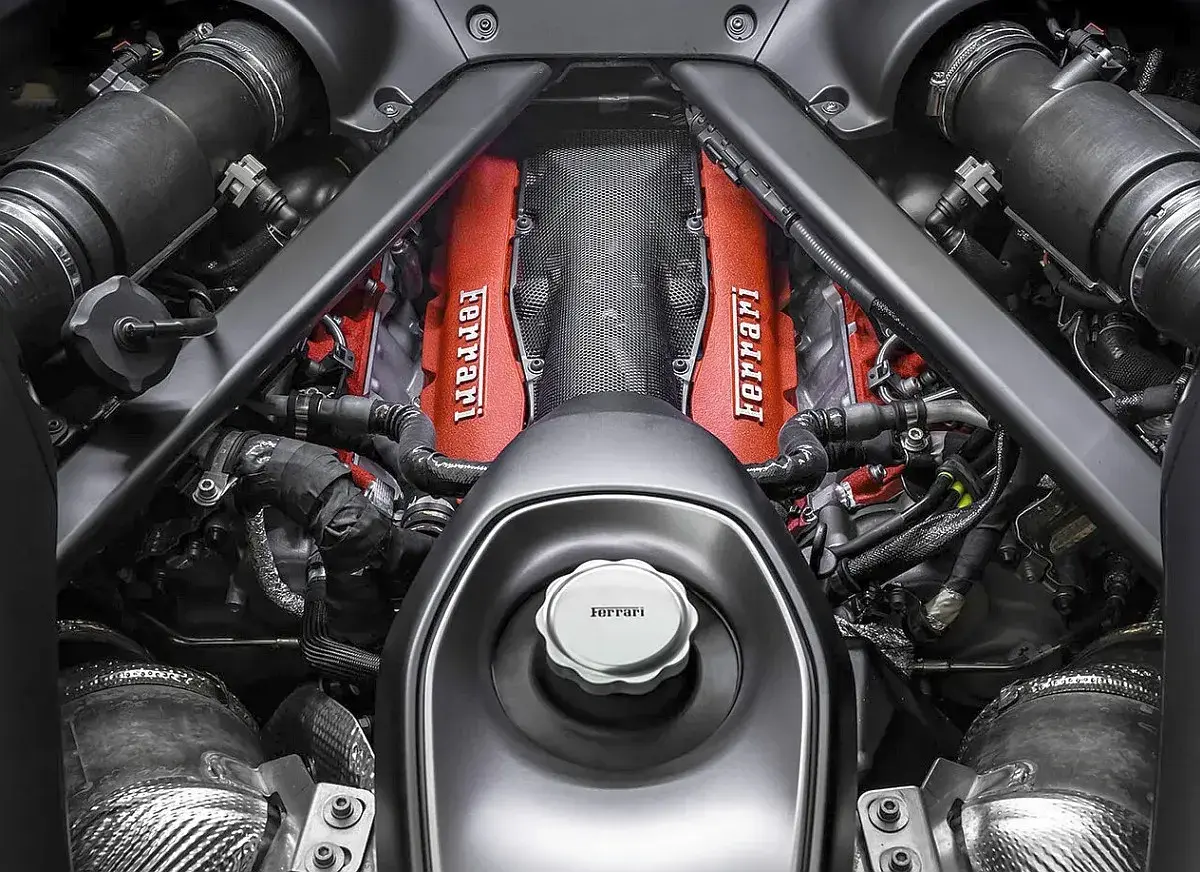 Silnik Ferrari v12, z czerwonymi pokrywami zaworów i charakterystycznym logo, gotowy do pracy.