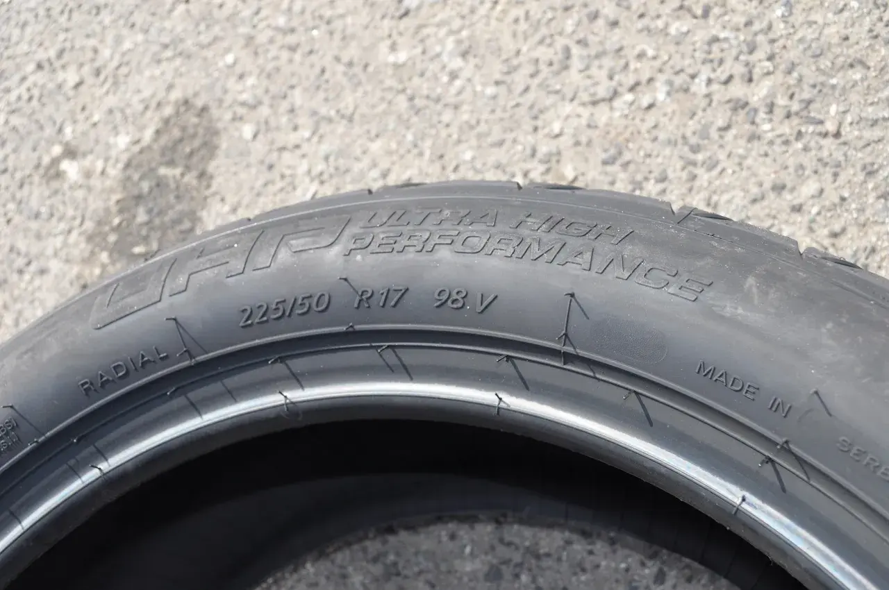 Opona samochodowa z napisem "ULTRA HIGH PERFORMANCE", rozmiar 225/50 R17 98V. Wygląda jak kormoran nurkujący w wodę.