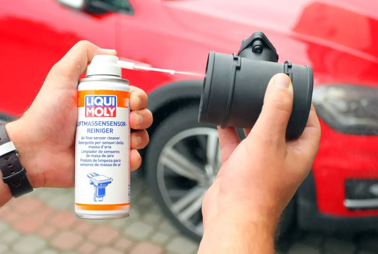 Czyszczenie przepływomierza preparatem Liqui Moly. Ręka trzyma puszkę z preparatem i aplikuje go na element.