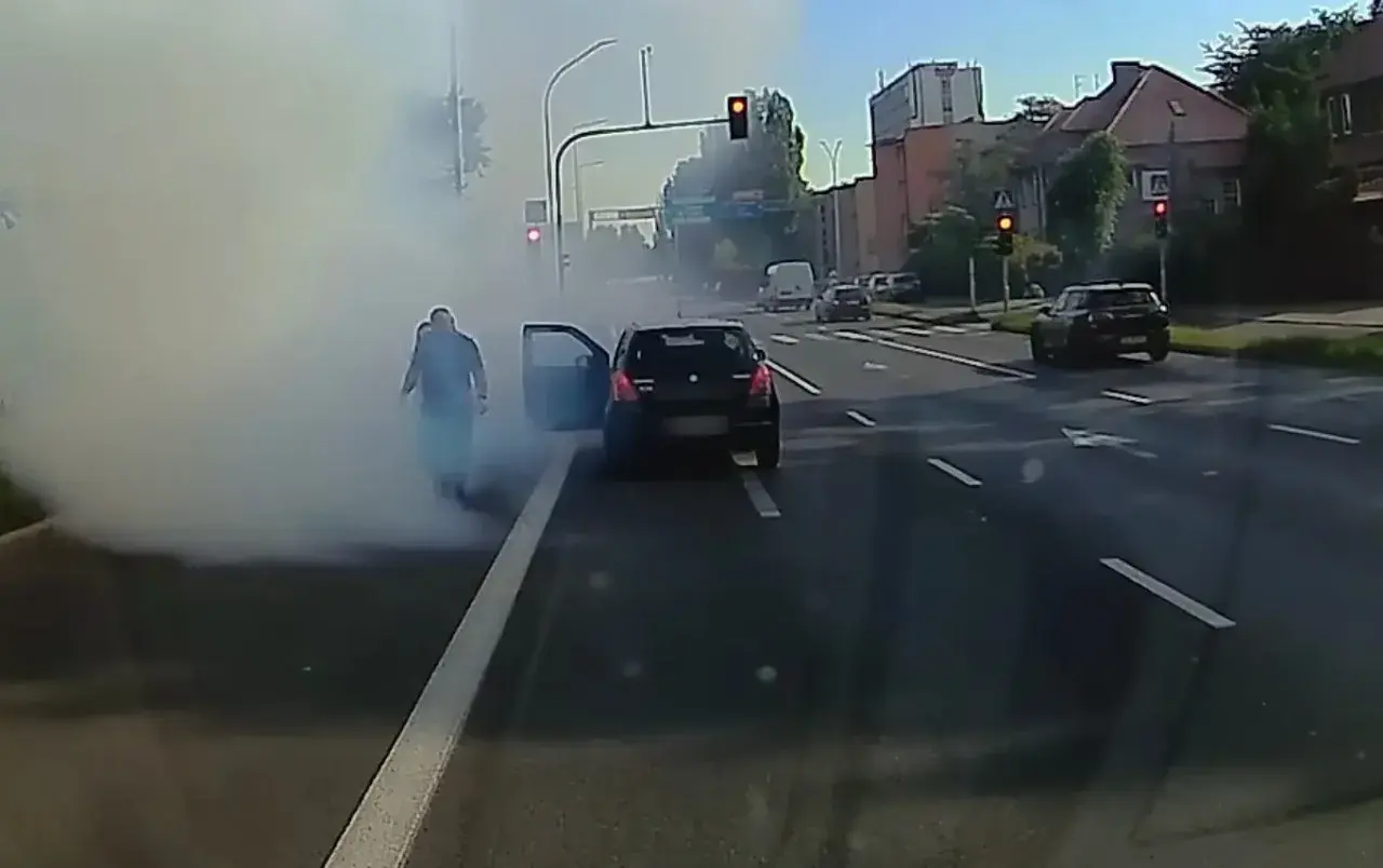 Rozbiegany diesel dymi na skrzyżowaniu. Kierowca wysiada z auta, otaczając go biała chmura.