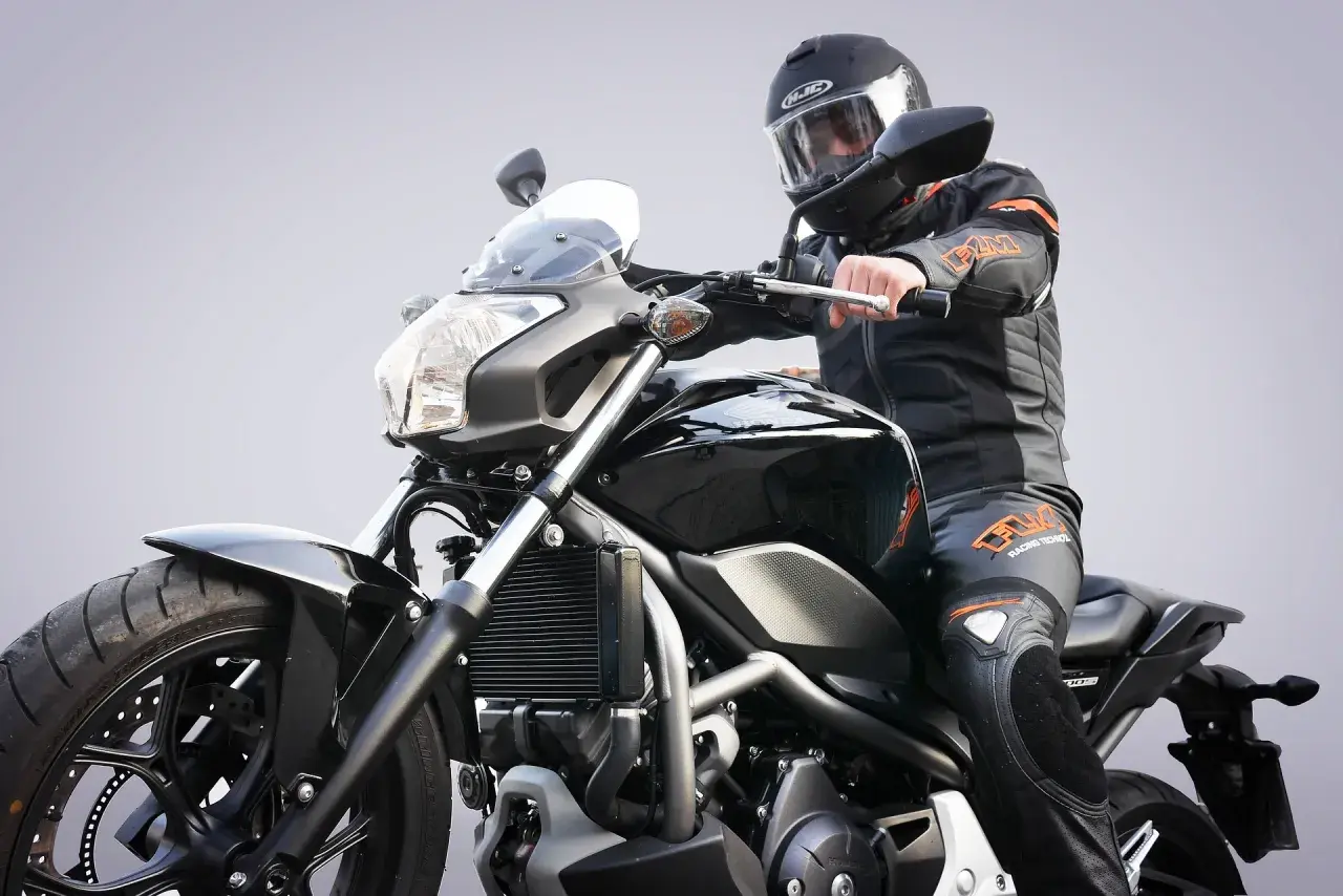 Motocyklista w kasku i kombinezonie siedzi na czarnym motocyklu. Zastanawiasz się, prawo jazdy a1 od ilu lat?