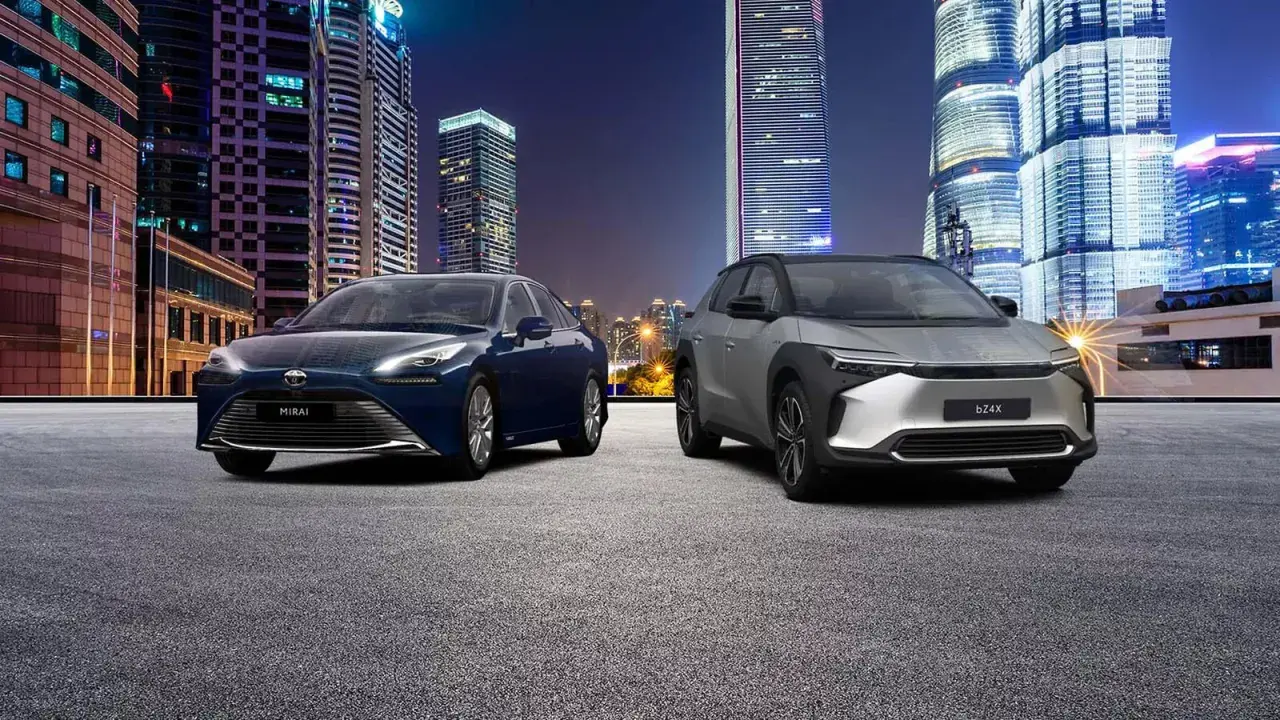 Dwa samochody, Toyota Mirai i bZ4X, na tle nocnego miasta. Zastanawiasz się, ile kosztuje samochód elektryczny?