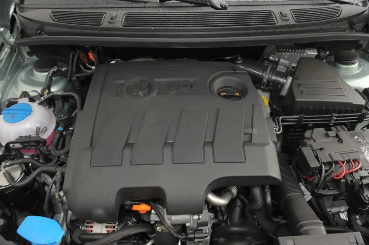 Silnik 1.6 TDI z widocznym osprzętem, przewodami i zbiorniczkiem płynu chłodniczego.