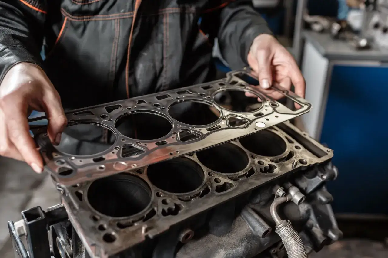 Mechanik trzyma nową uszczelkę pod głowicą, gotową do montażu. Poznaj koszt wymiany uszczelki pod głowicą.