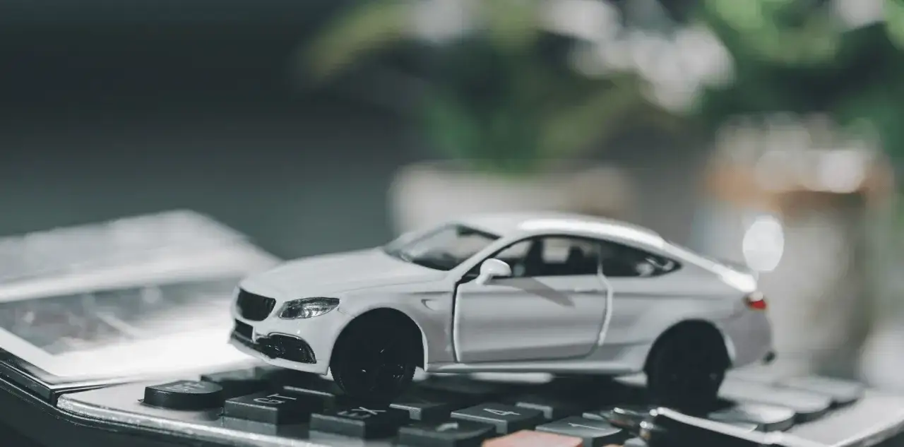 Biały model samochodu na klawiaturze kalkulatora. Czy to rozwiązanie dla Ciebie? Dowiedz się, co to leasing i jak działa.