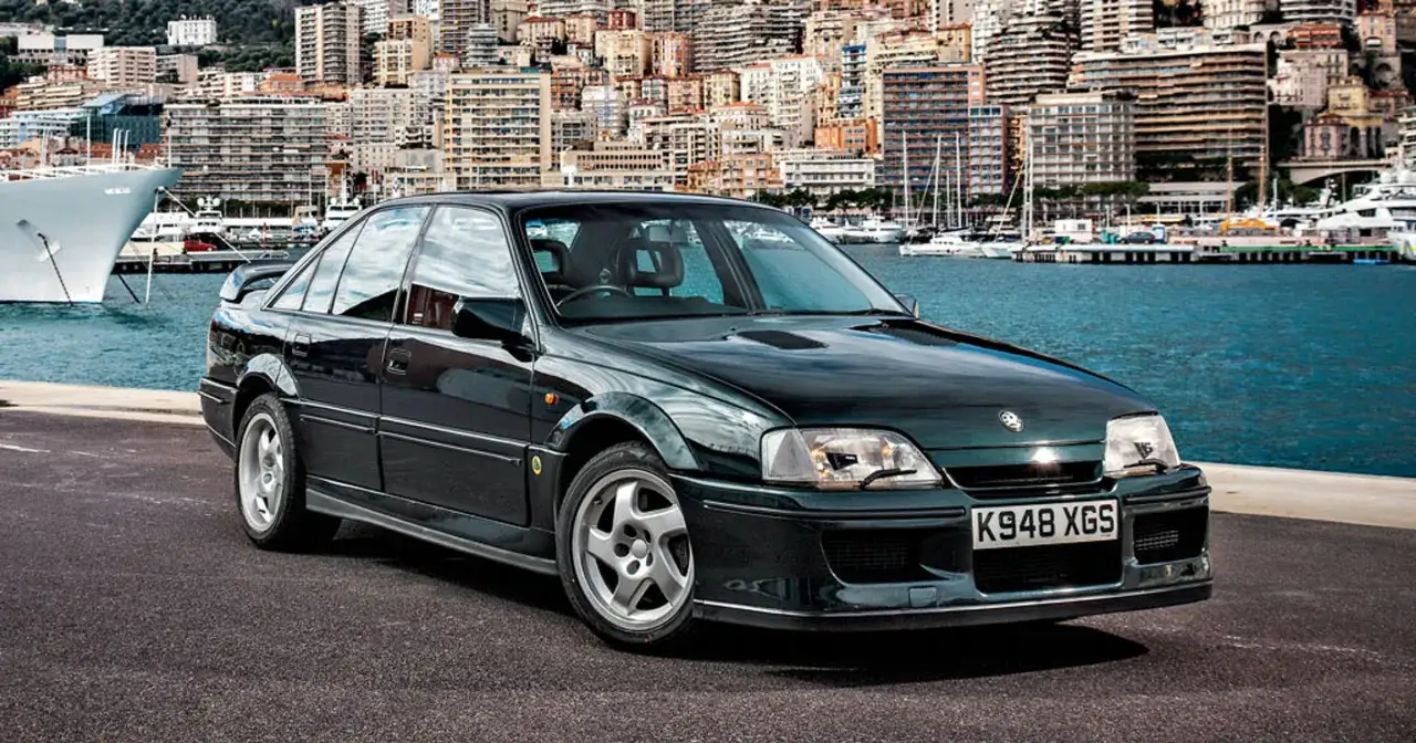 Czarny Lotus Omega z tablicą K948 XGS stoi nad wodą, w tle port z jachtami i budynkami.