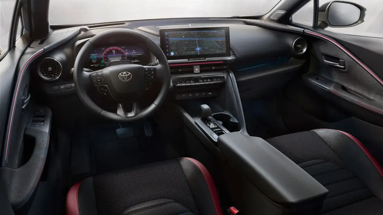 Wnętrze Toyota C-HR 2025: cyfrowy kokpit, duży ekran multimediów, sportowe fotele z czerwonymi akcentami i nowoczesna konsola środkowa.