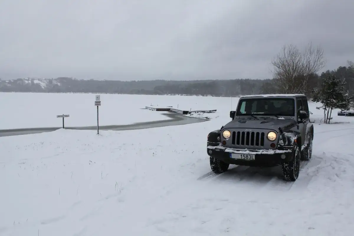 Szary Jeep z napędem Haldex na śnieżnej drodze nad zamarzniętym jeziorem.