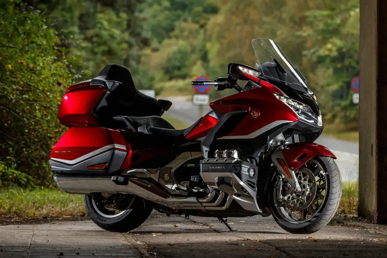 Lśniący, czerwony motocykl Honda Goldwing z dużymi kuframi, gotowy na długą podróż.