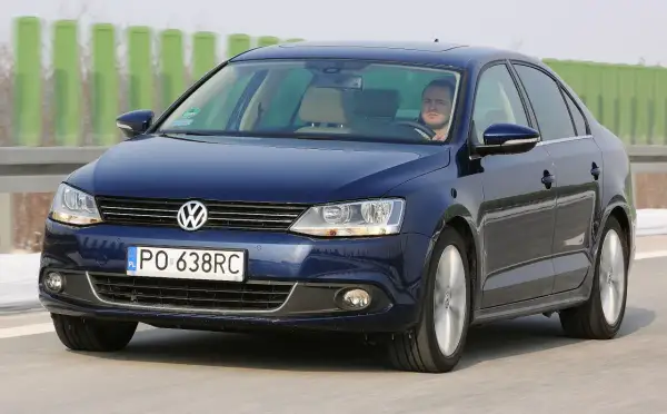 Ciemnoniebieski VW Jetta MK6 jedzie autostradą. Za kierownicą siedzi mężczyzna.