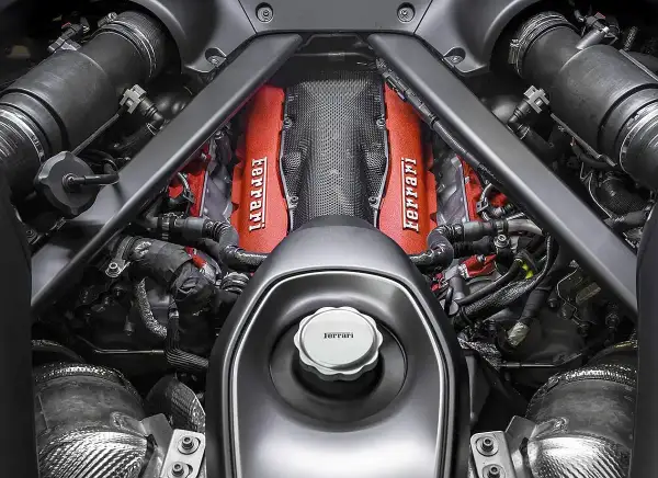 Silnik Ferrari v12, z czerwonymi pokrywami zaworów i charakterystycznym logo, gotowy do pracy.