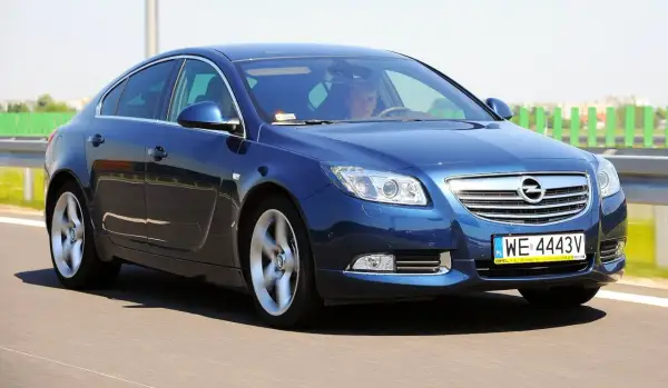 Niebieski Opel Insignia 2.0 CDTI pędzi po drodze. Kierowca skupiony na trasie.