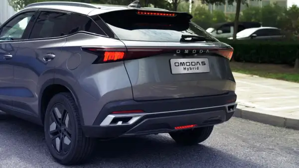 Szary OMODA 5 Hybrid z tyłu, z widocznym napisem "OMODA Hybrid" na klapie bagażnika. Nowoczesne światła LED i sportowy dyfuzor.