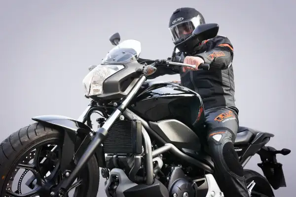 Motocyklista w kasku i kombinezonie siedzi na czarnym motocyklu. Zastanawiasz się, prawo jazdy a1 od ilu lat?