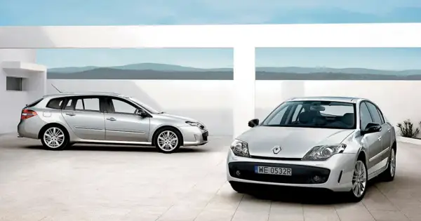 Dwa srebrne Renault Laguna 3 2.0 dCi: kombi i sedan, stojące na nowoczesnym placu z widokiem na góry.